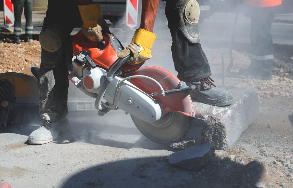 Hand arm vibration syndrome, Builder worker with cut-off machine power tool breaking concrete at road construction site